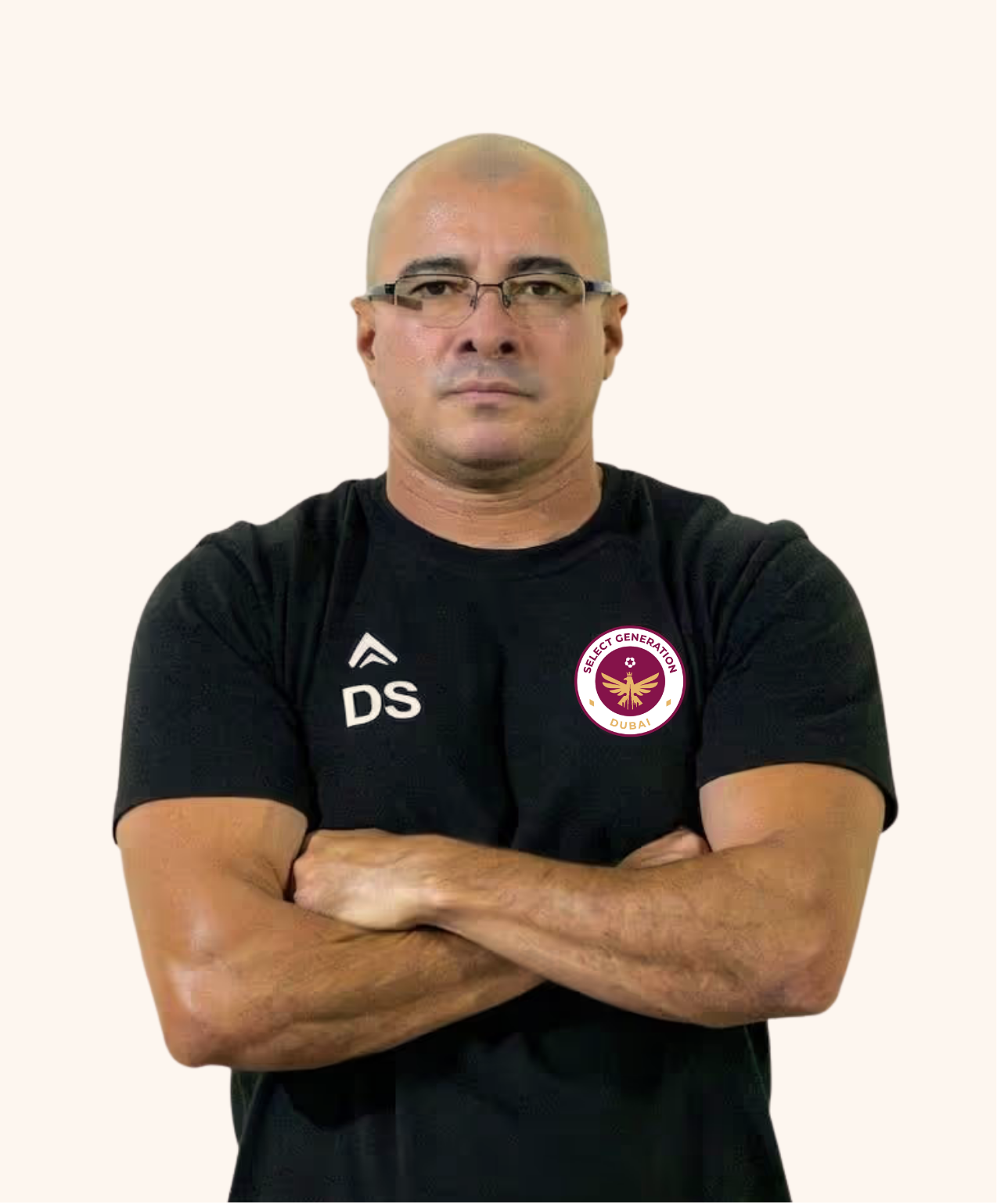 Man with arms crossed wearing a black Adidas t-shirt and a black cap against a plain light background.
