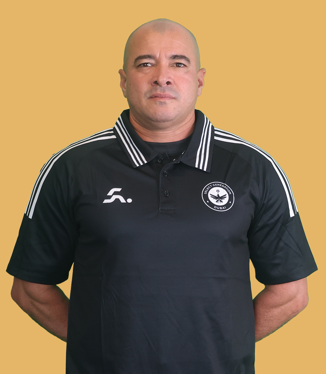 Man with arms crossed wearing a black Adidas t-shirt and a black cap against a plain light background.