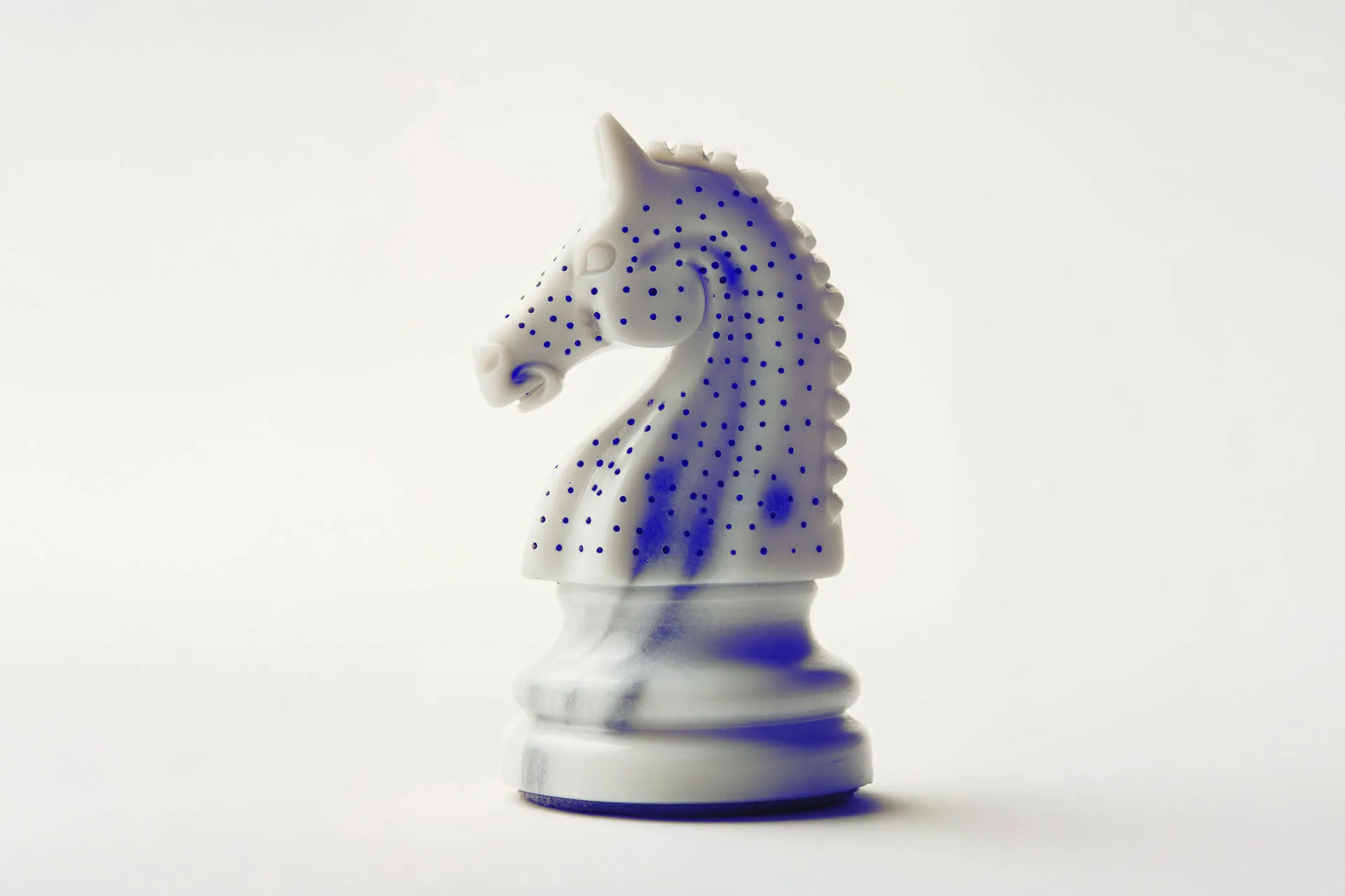 Weiße Schachfigur Springer mit blauen Punkten als Sinnbild für strategisches Design statt Dekoration