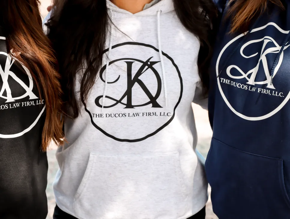 Three people wearing hoodies with The Ducos Law Firm, L.L.C. logo in black, gray, and navy colors.