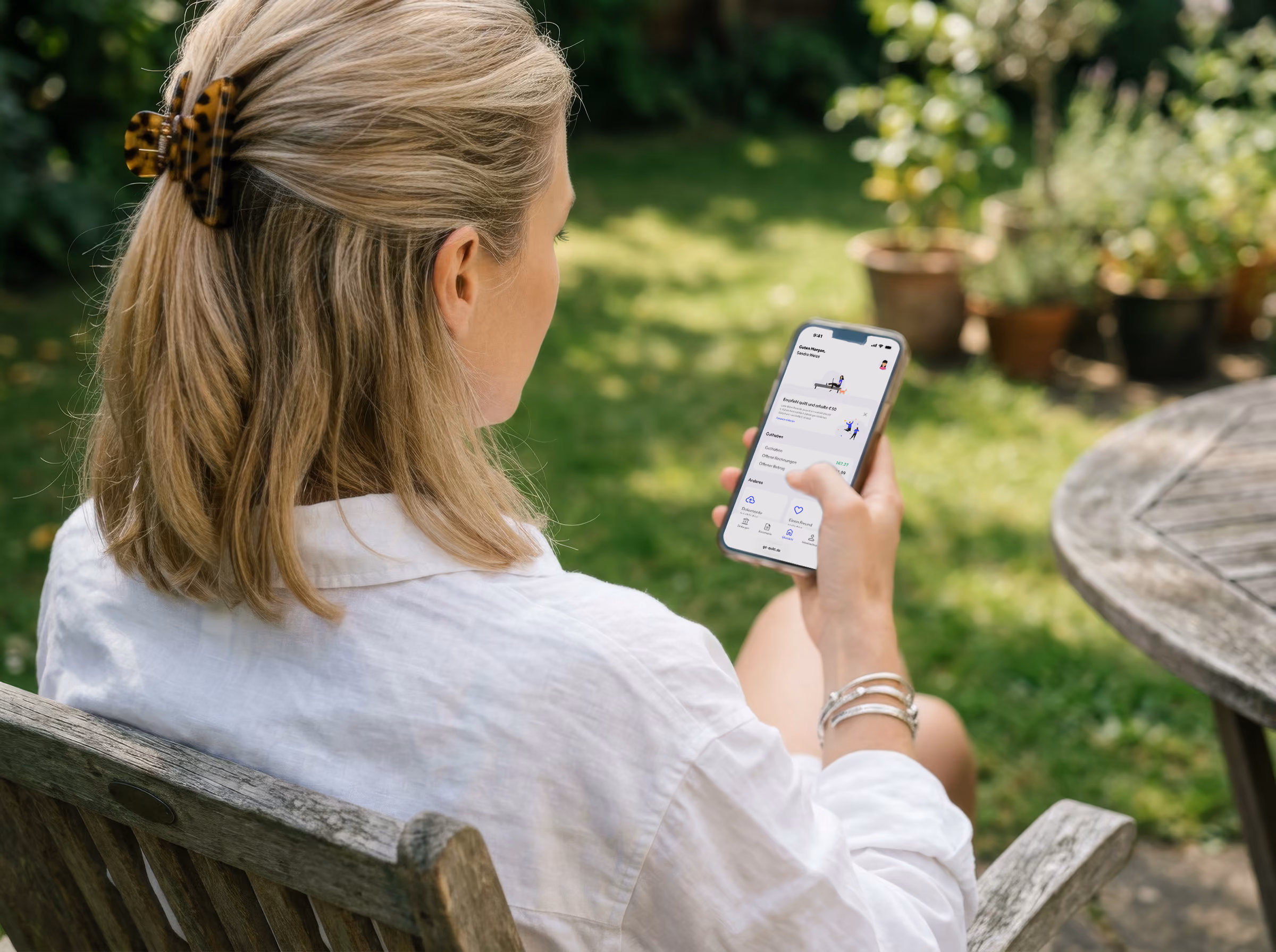 Woman sits outside on a bench and uses a cell phone with an app in the garden.