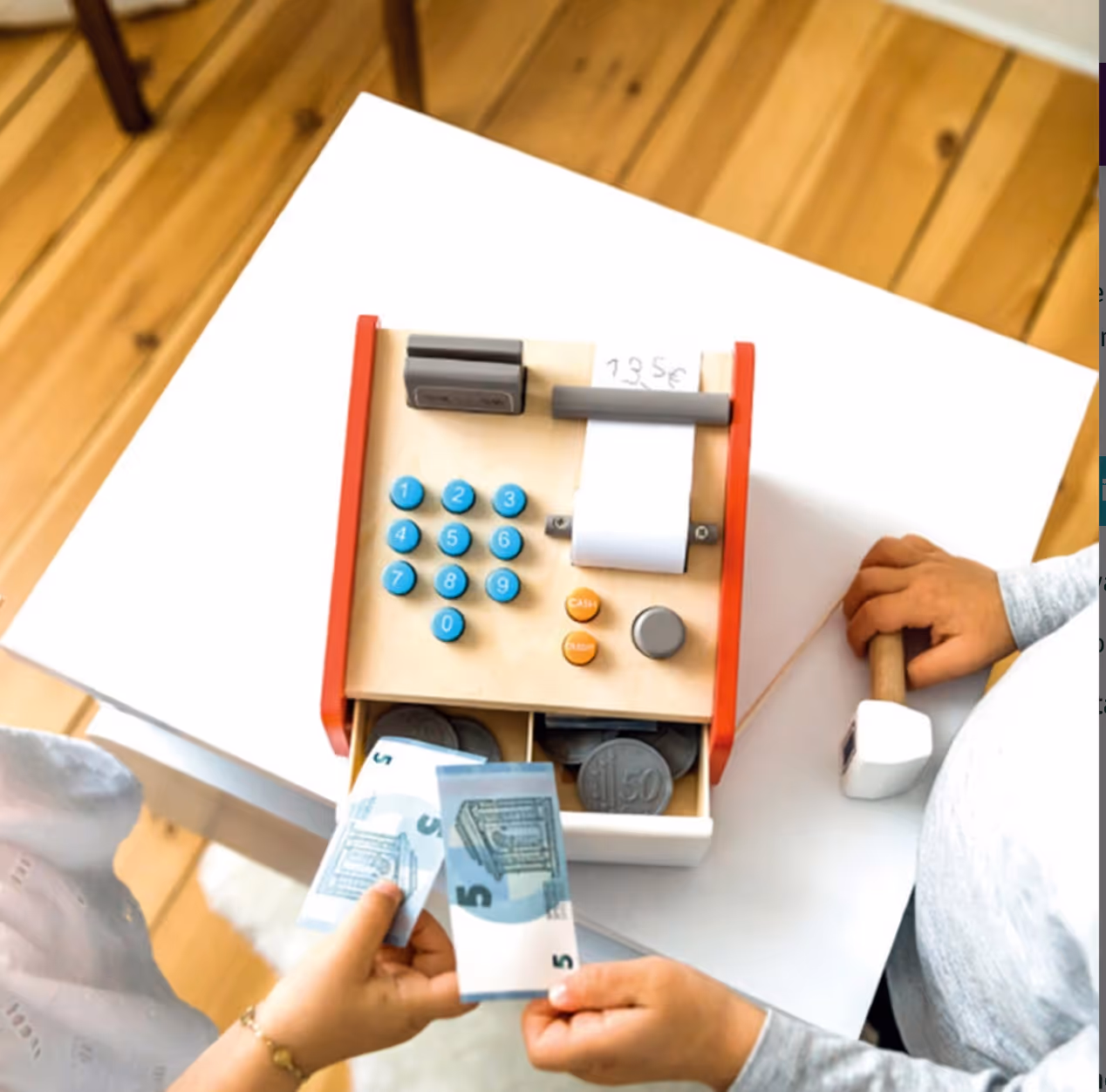 Twee kinderen spelen met een houten speelgoedkassa en nepgeld op een witte tafel.