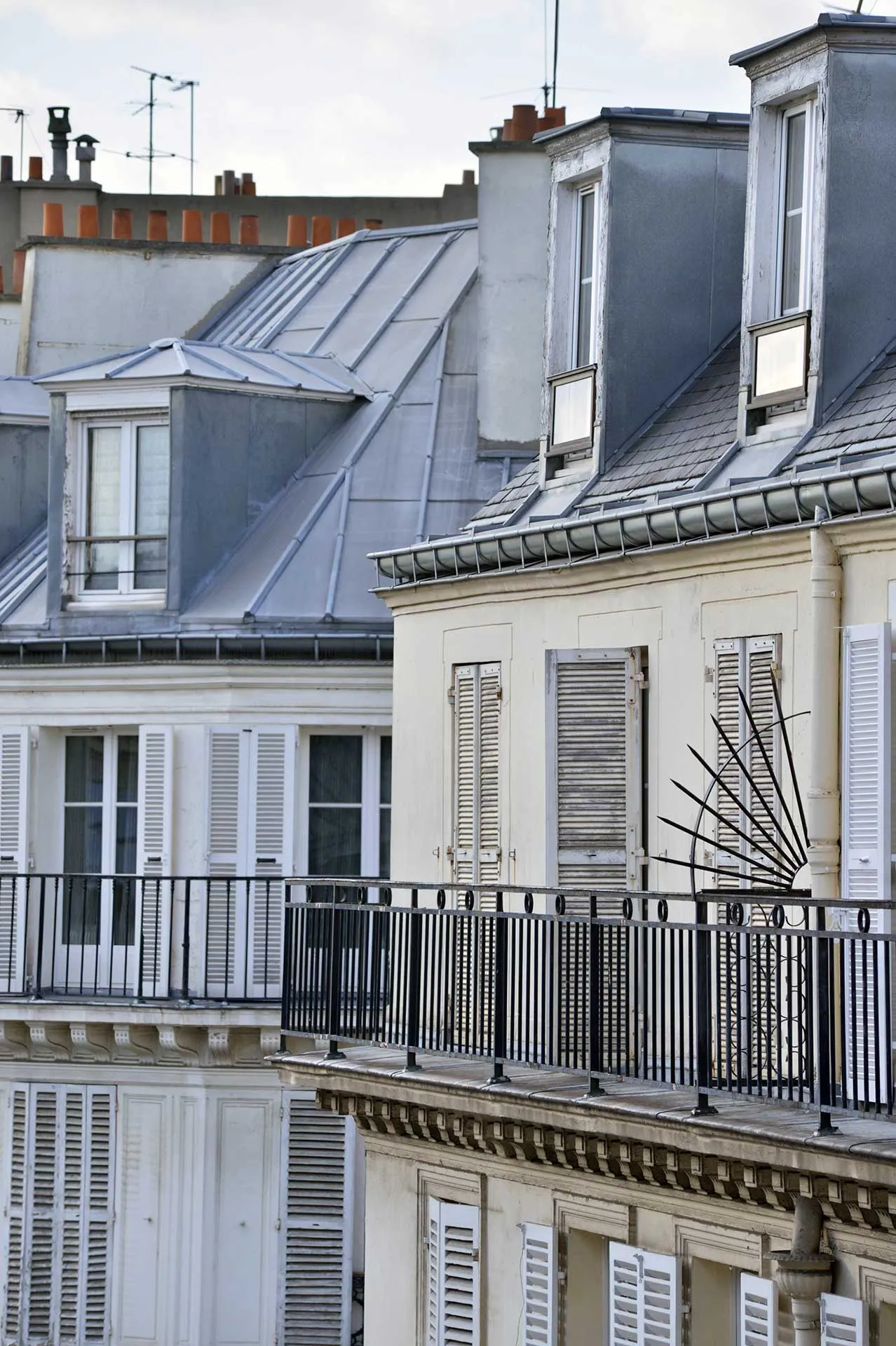 Façades d'immeubles haussmanniens et de l'hôtel Eugénie avec toits mansardés sous un ciel partiellement nuageux.