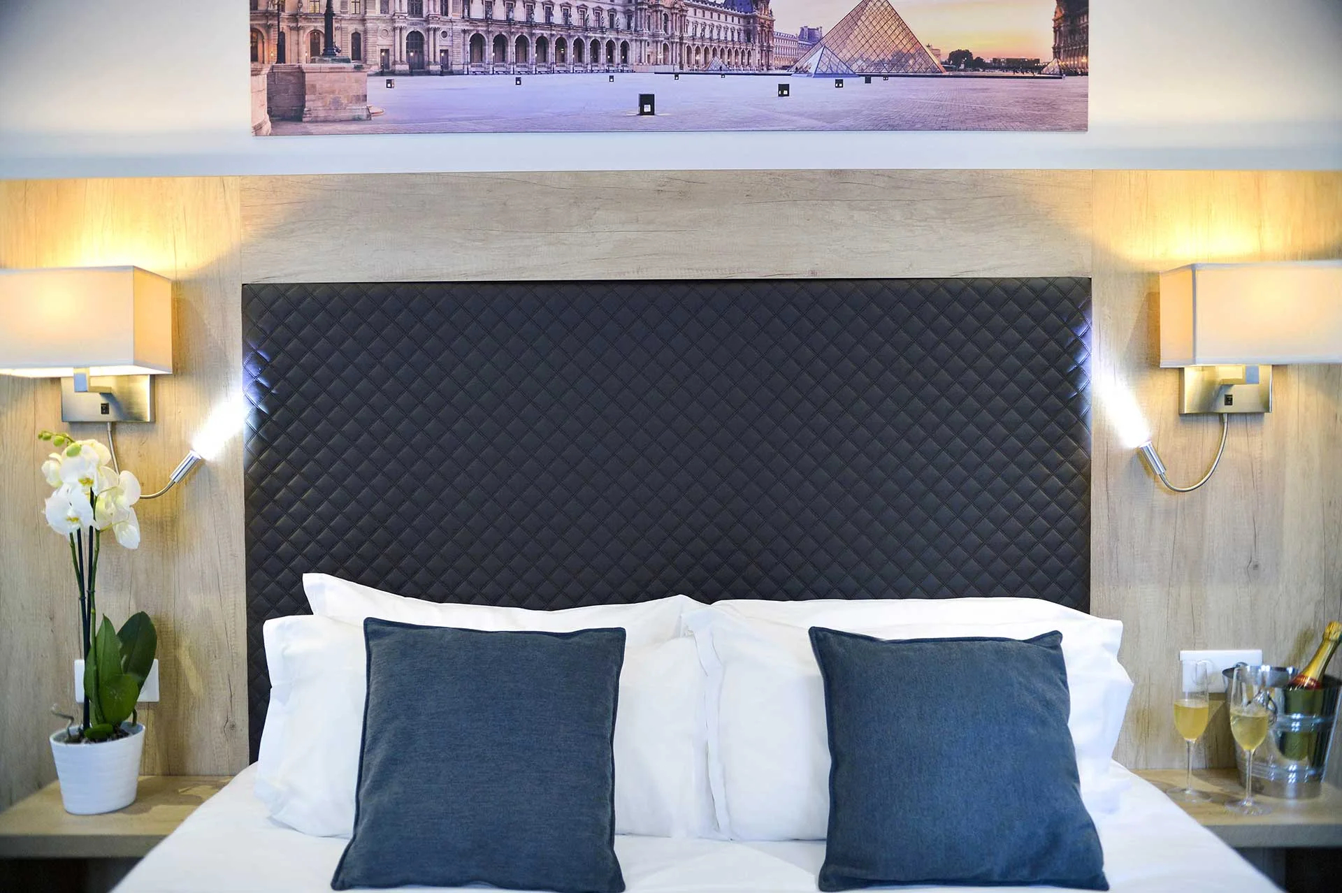 Lit de nos chambre Supérieure Triple avec drap blanc, meuble en bois et tableau de paris sur le murs.