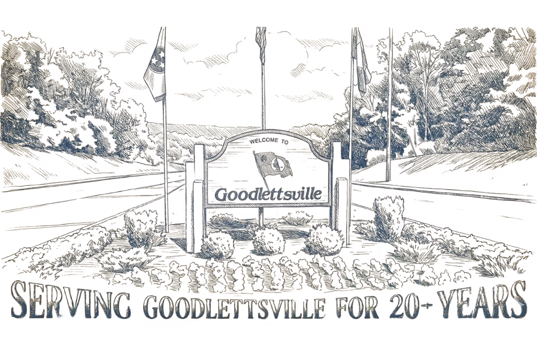 Welcome to Goodlettsville sign on roadside with three flagpoles and surrounding bushes.