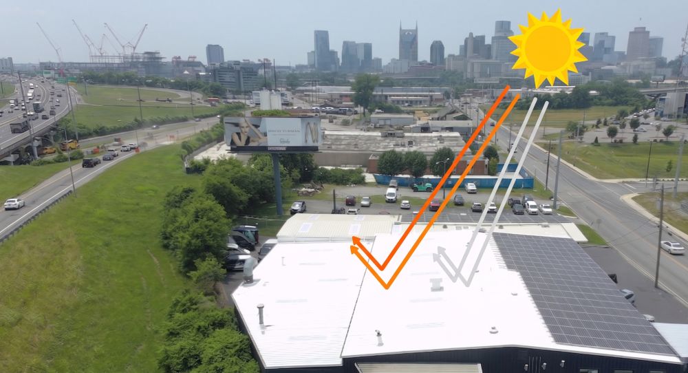 City skyline view with a rooftop showing sunlight reflection and solar panels on one side.