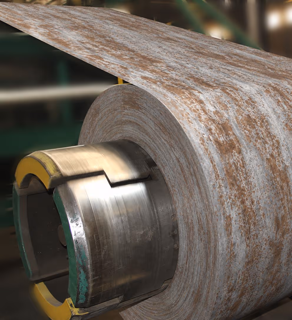 Close-up of a large rusted metal coil roll on industrial machinery.