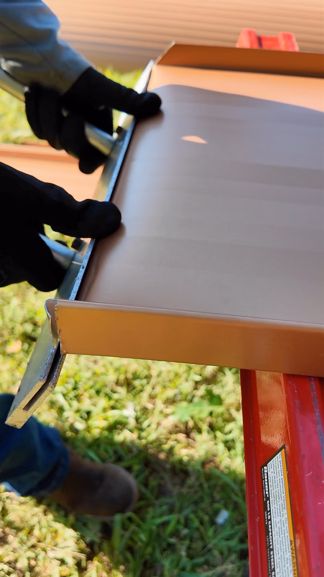 Hand seamer bending a standing seam panel end to lock into the roof edge