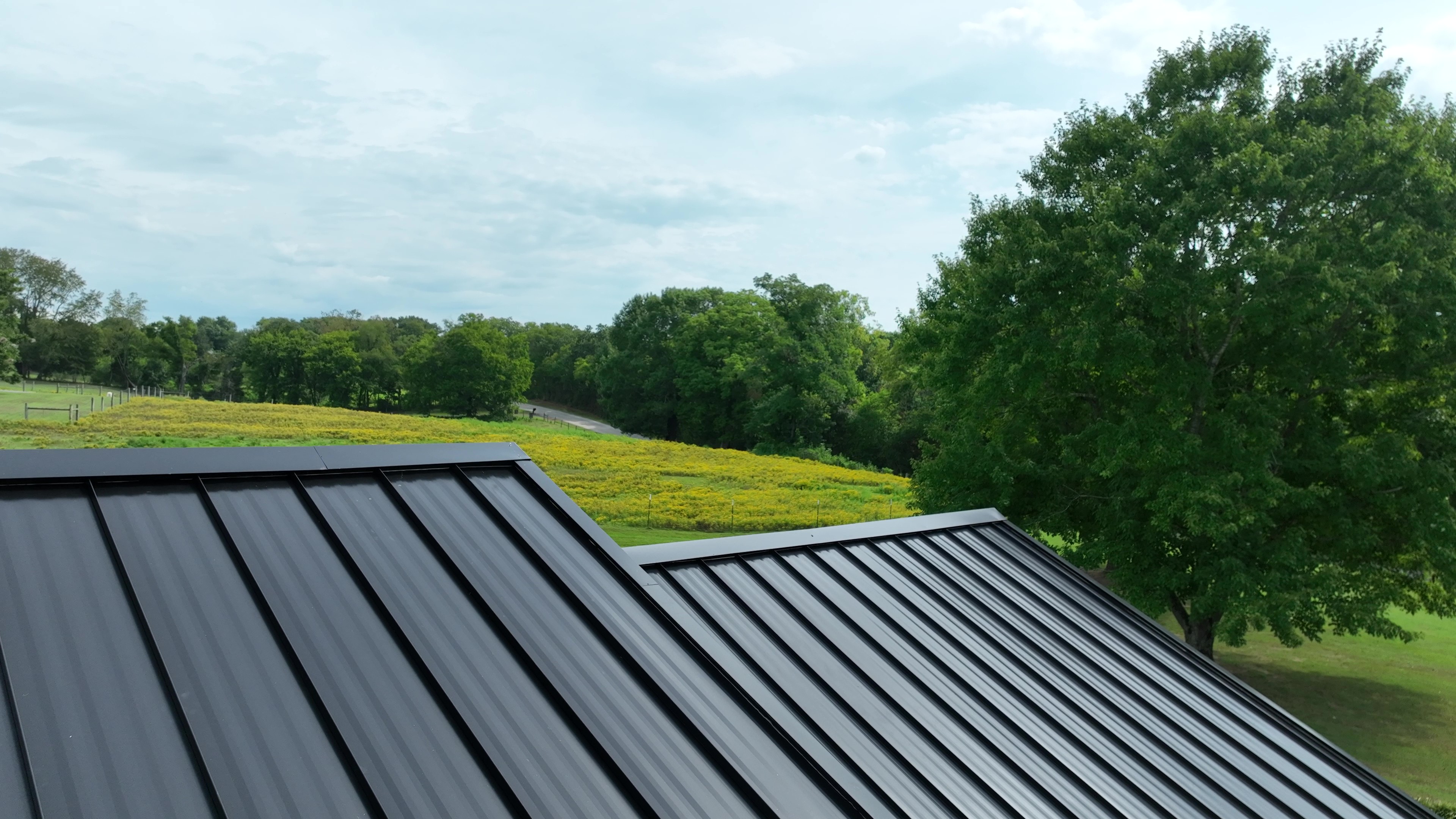 Ridge level view of a black standing seam metal roof overlooking pasture in Hartsville, Tennessee