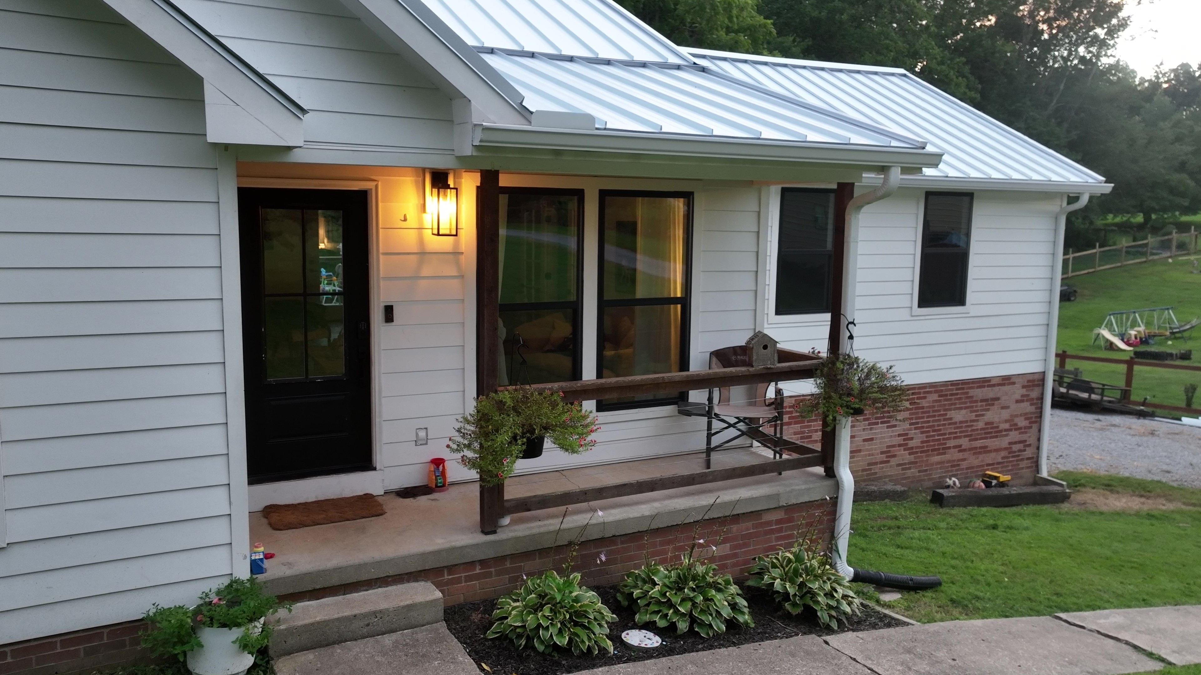 White standing seam metal porch roof at dusk on a white farmhouse in Ashland City, Tennessee