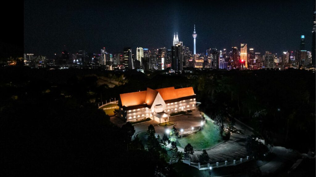 A nighttime aerial view of Whitehouse @ The Estate on Federal Hill, a serene heritage venue that stands in contrast to the illuminated Kuala Lumpur city skyline, perfectly capturing a space that feels nothing like the city.