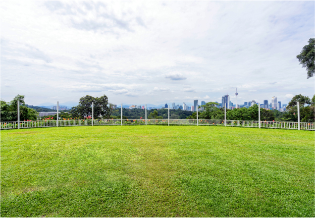 the The wide, open garden at Whitehouse @ The Estate on Federal Hill, a peaceful and spacious event area with a panoramic view of the Kuala Lumpur city skyline.