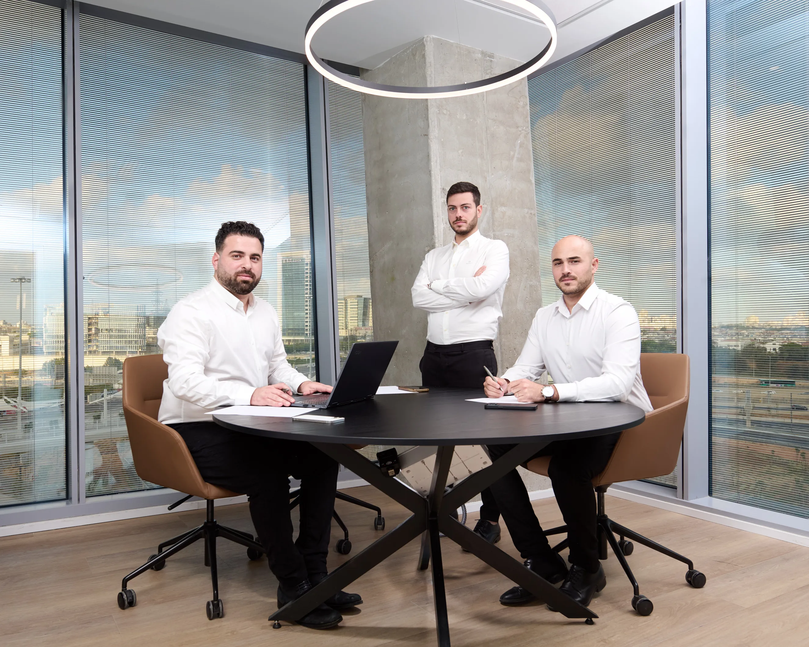 צוות של שלושה שותפים עסקיים בחדר ישיבות בראשון לציון. צילומי תדמית לעסקים באווירה דינמית ומגובשת המדגישה שיתוף פעולה. תמונה קבוצתית המיועדת לאתר העסקי.