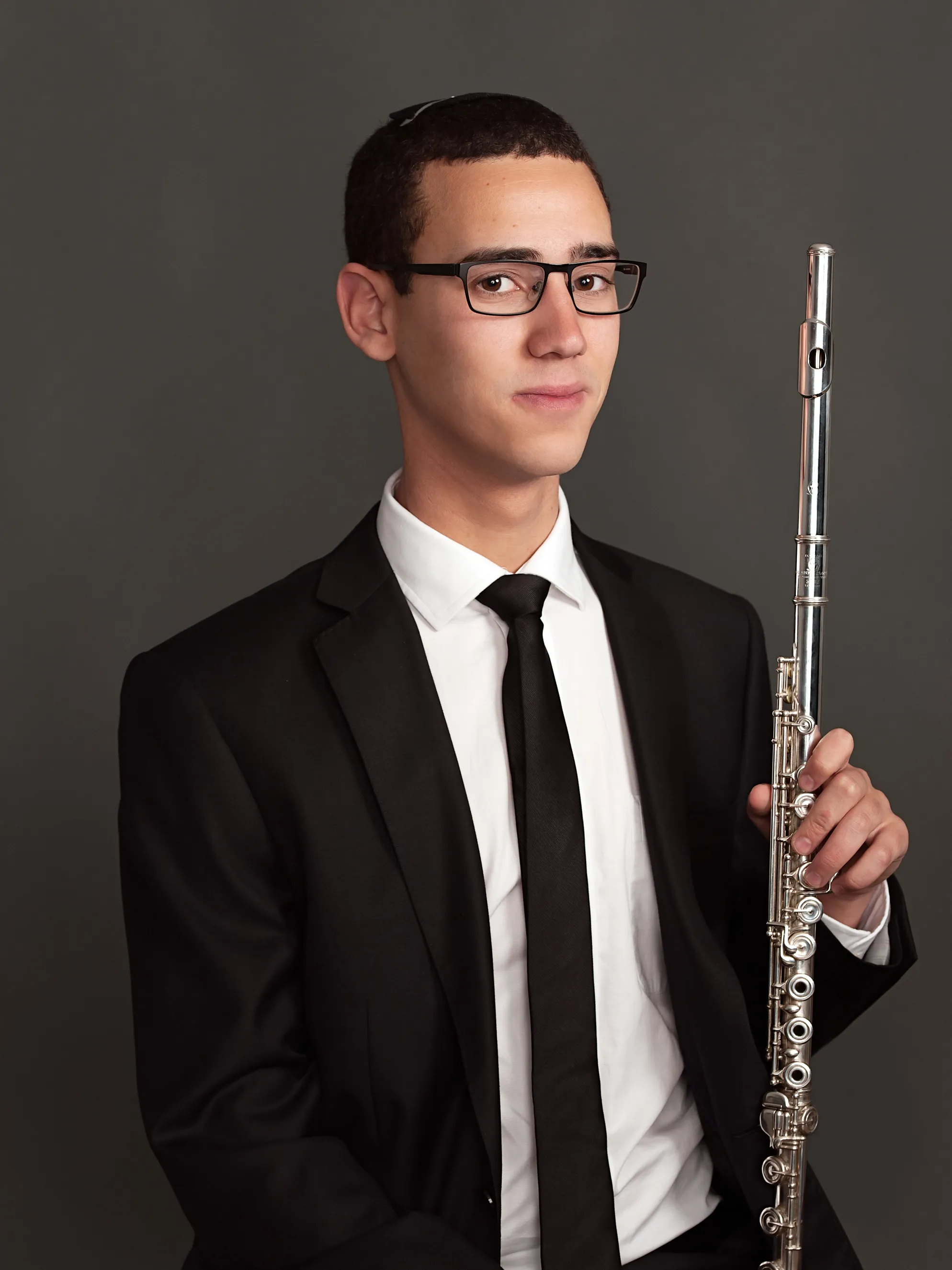 פורטרט מוזיקאי איכותי לשימוש מקצועי ופרסום של נגן חליל צעיר בסטודיו, במבט מלא ריכוז ותשוקה מוזיקלית.