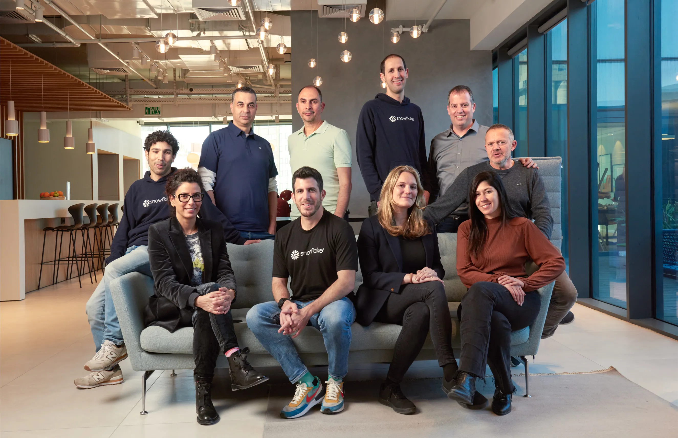 צוות עובדים בלובי משרדים מודרני ברעננה. מיתוג אישי באווירה דינמית ומגובשת המדגישה שיתוף פעולה. תמונה קבוצתית המיועדת לאתר העסקי.