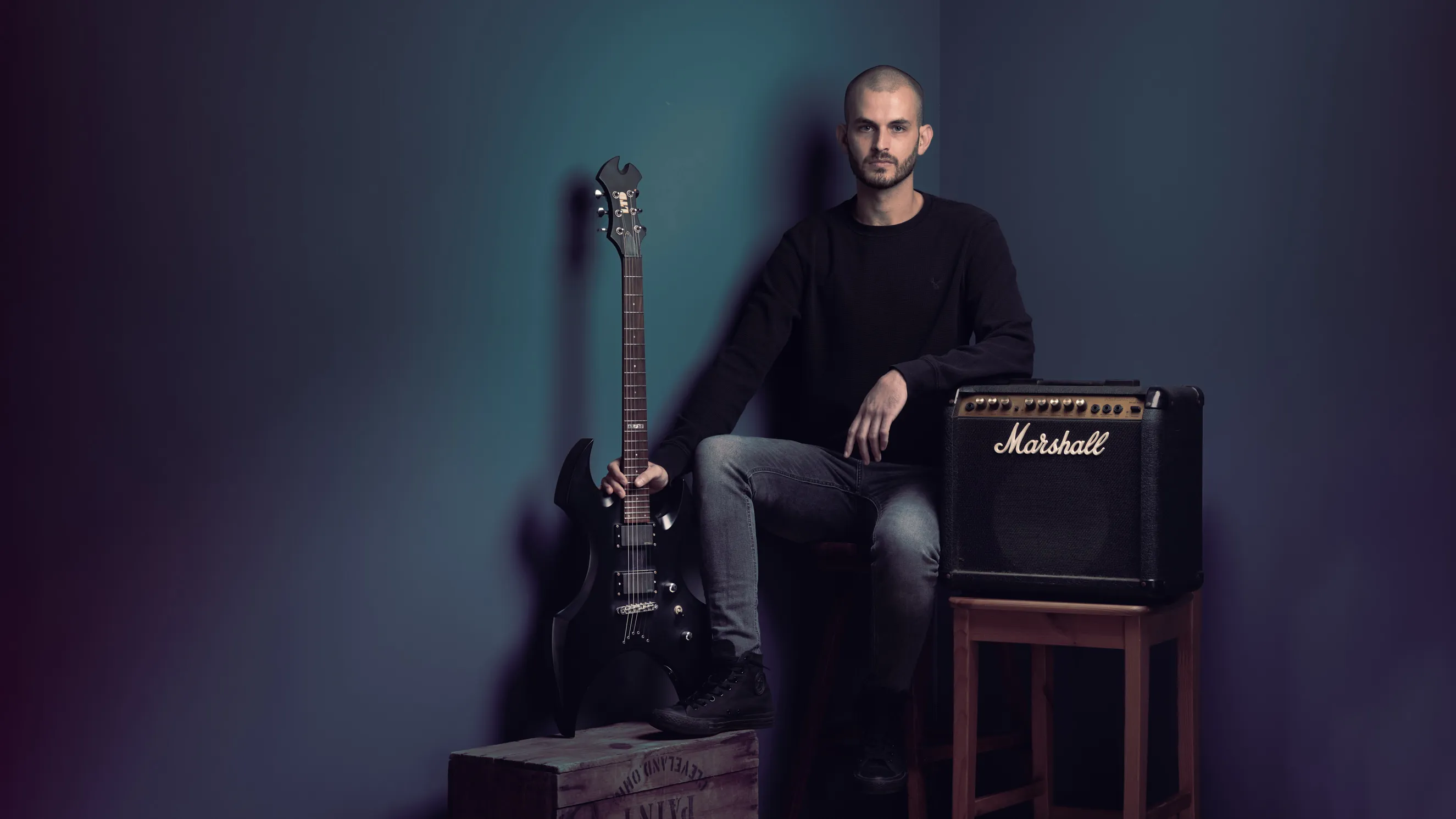 גיטריסט מרעננה בסטודיו בעיבוד אמנותי. תמונות תדמית למוזיקאים באווירה אמנותית המדגישה את הקשר לכלי הנגינה. צילום מוזיקאים מקצועי ליחסי ציבור.