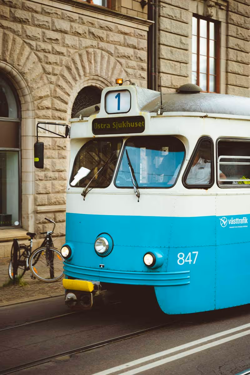 Blåvit spårvagn nummer 847 på linje 1 mot Östra Sjukhuset i stadsmiljö med cyklar och stenbyggnad i bakgrunden.