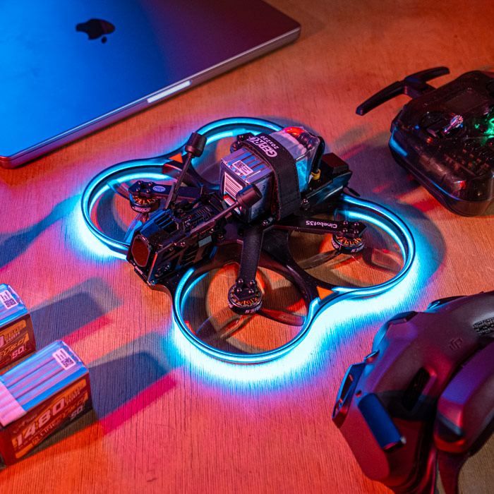 Black quadcopter drone with blue glowing circular guards and mounted camera on brown gradient background.