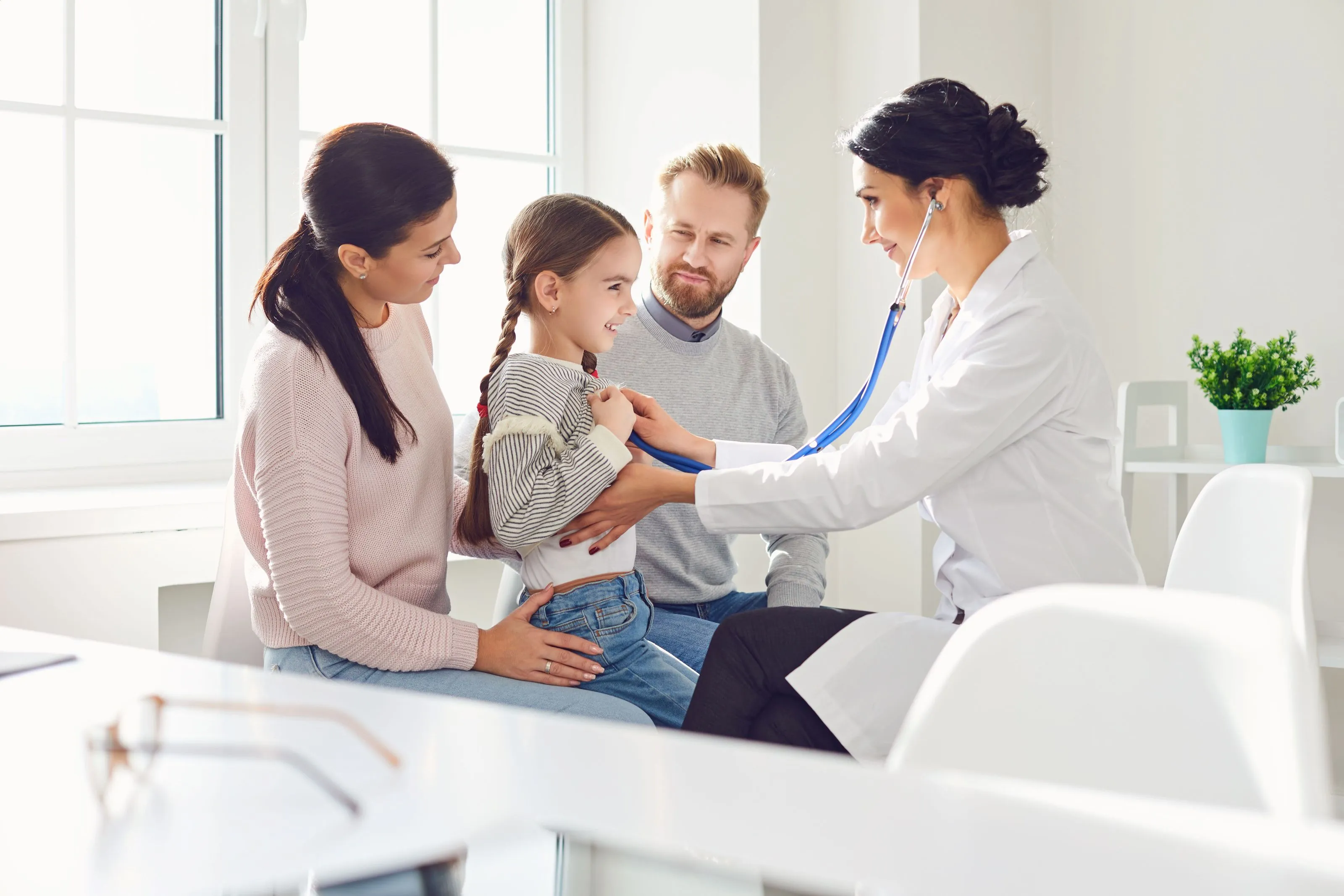 A group of people standing around a woman in a doctor's office.