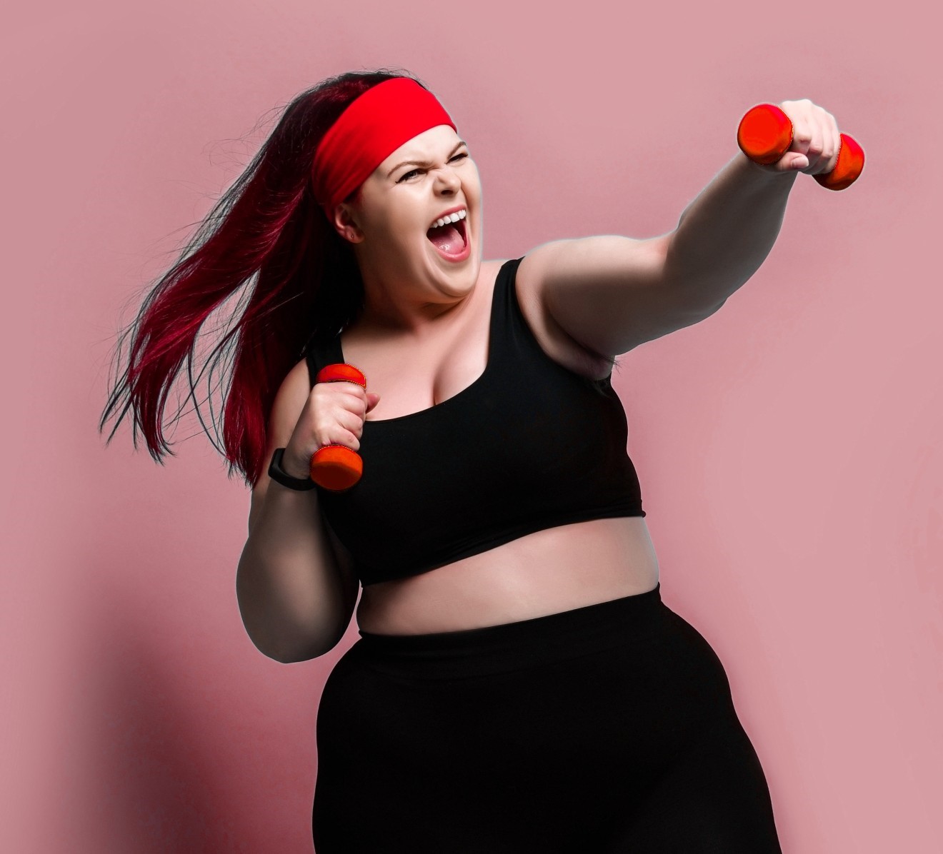 A woman with a red headband holding two dumbs.