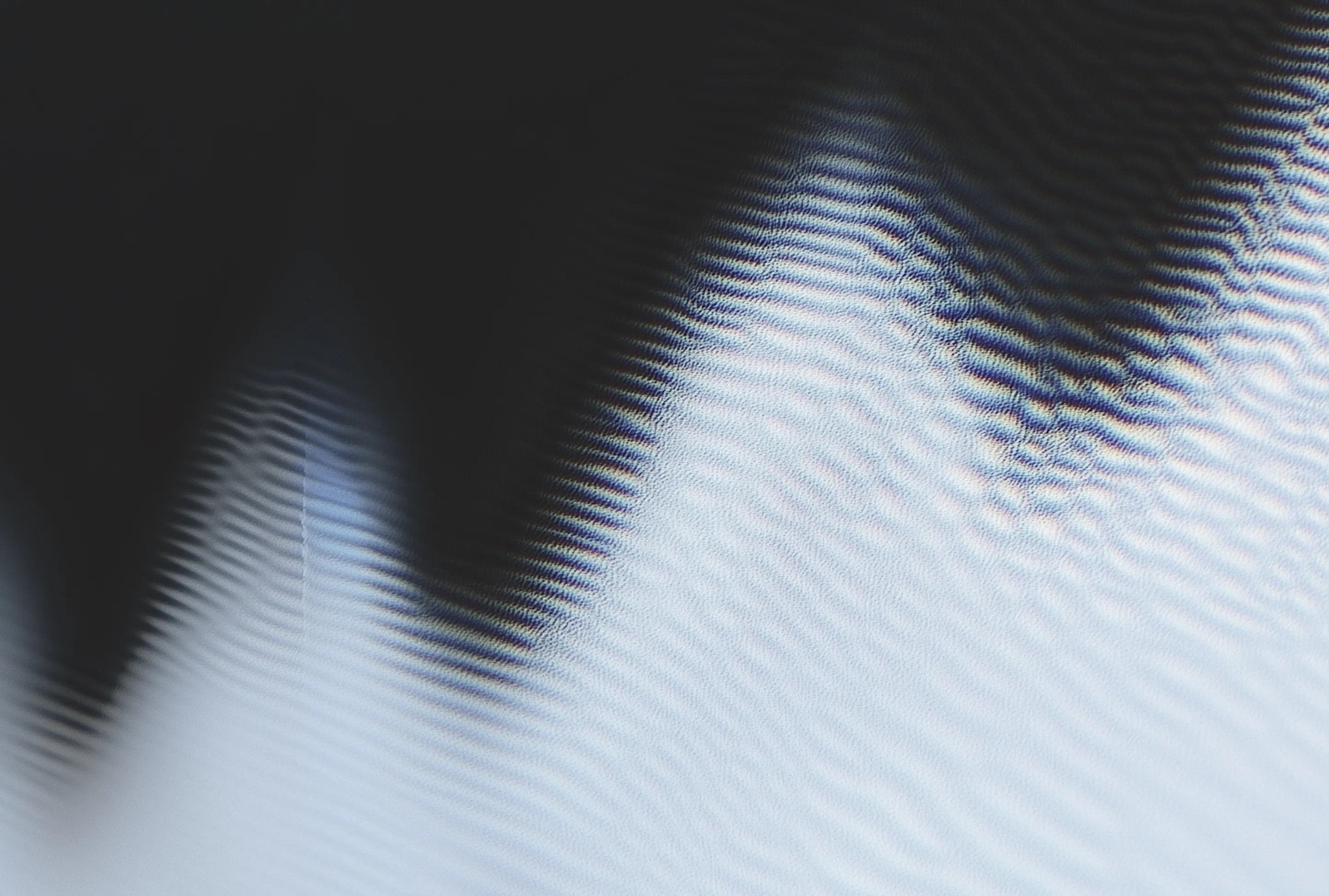 Close-up of a pattern with wavy, ripple-like lines creating a gradient from dark to light tones.