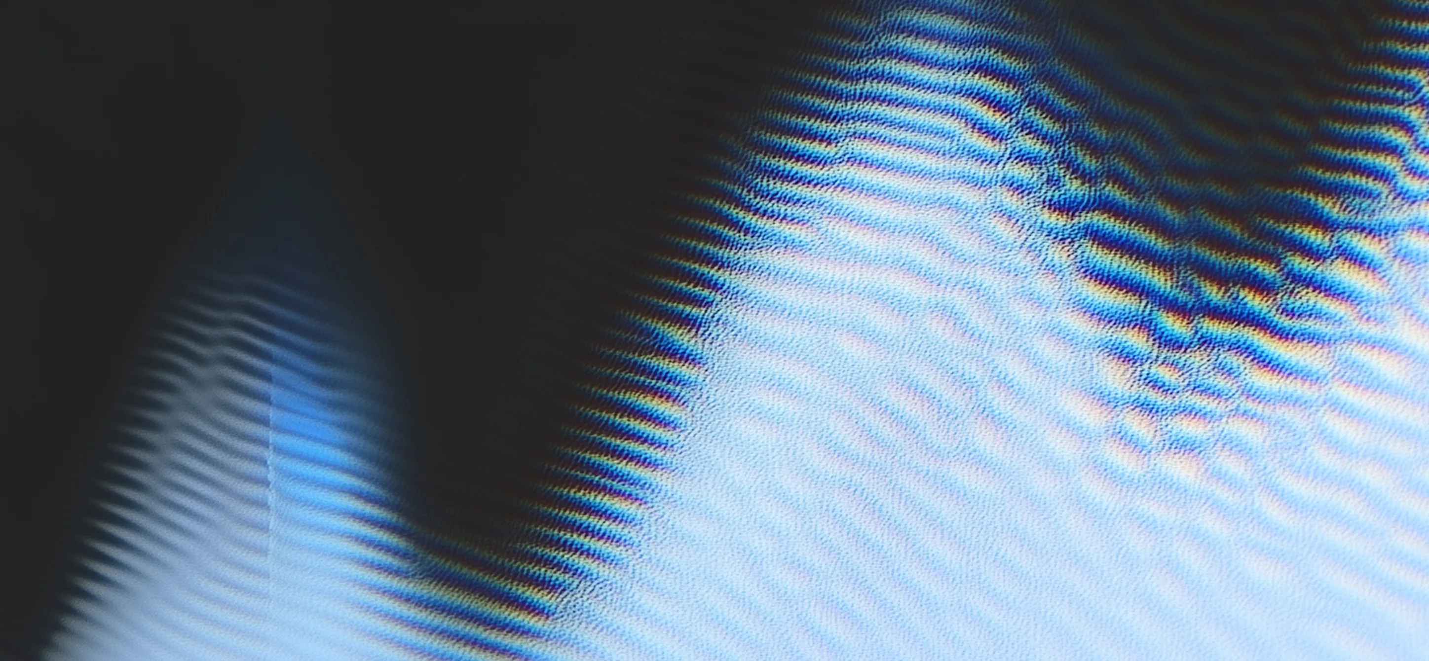 Close-up of black curved lines creating rainbow-colored interference patterns on a light surface.