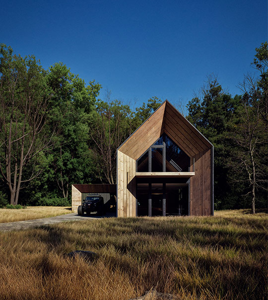 Silhouette of a hand holding a square perfume bottle against a bright background.
