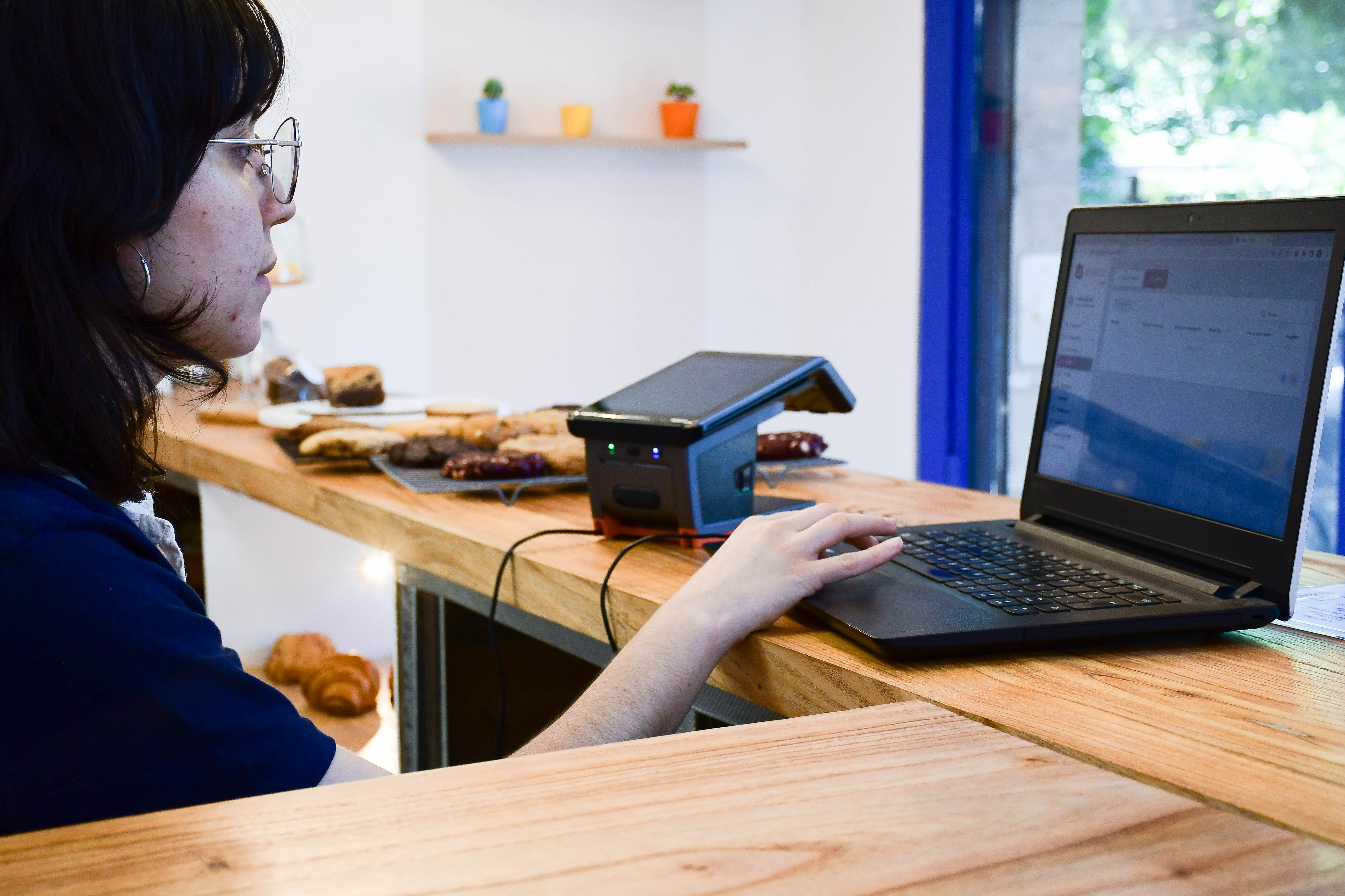 Comerciante con la terminal Alleata y su notebook en el mostrador