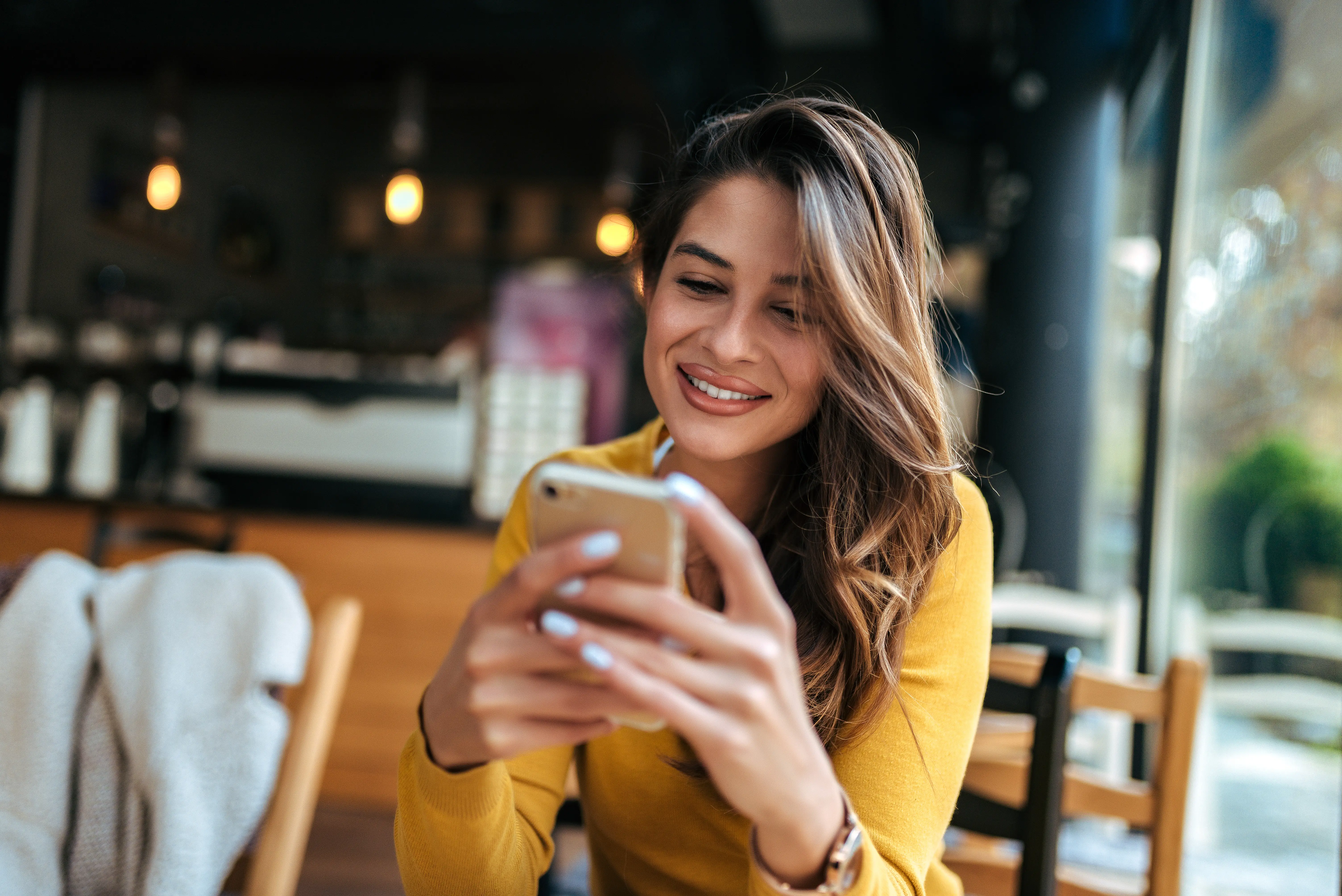 A woman sitting at a table looking at her cell phone.