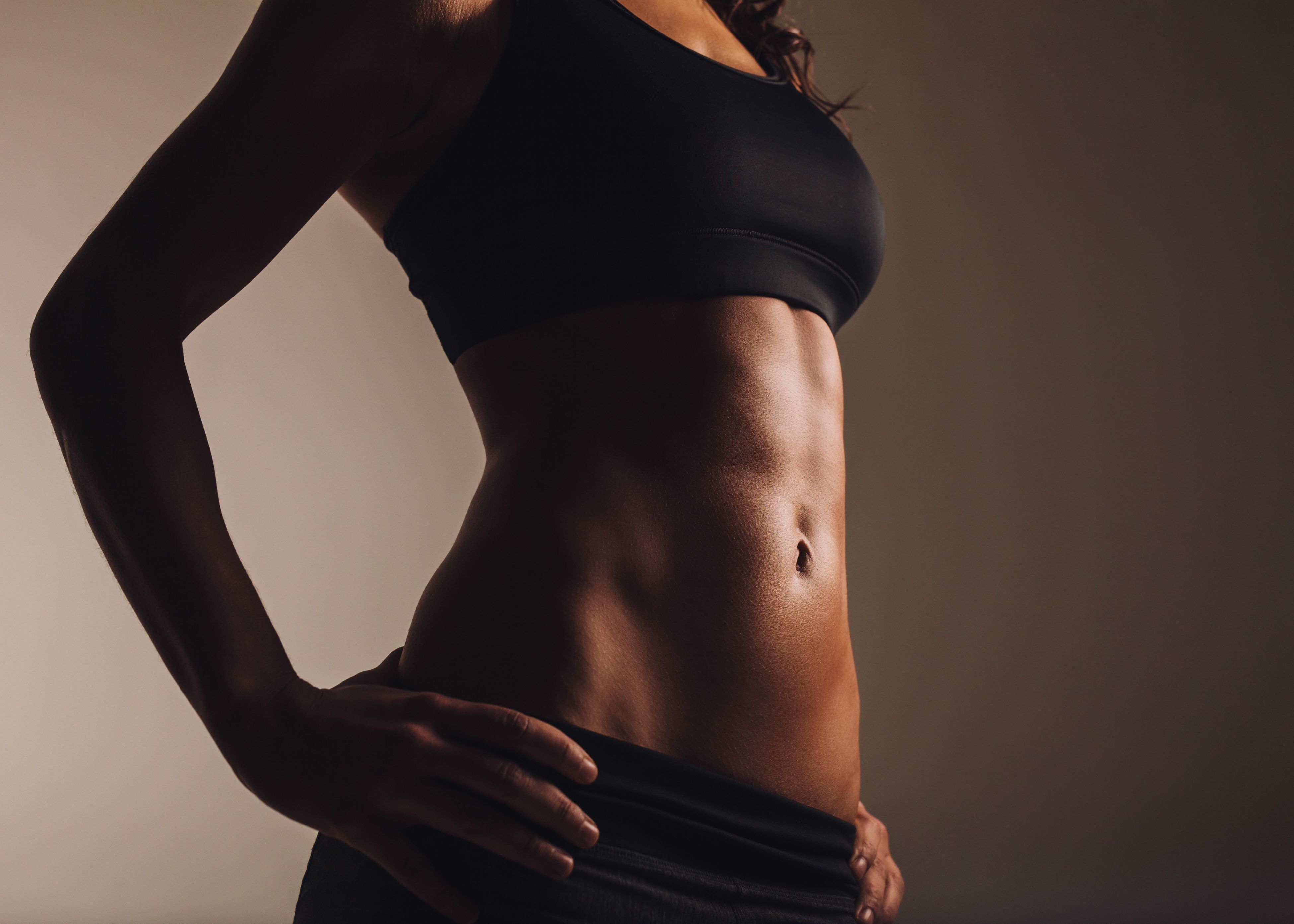 woman's abs wearing black shorts and sports bra