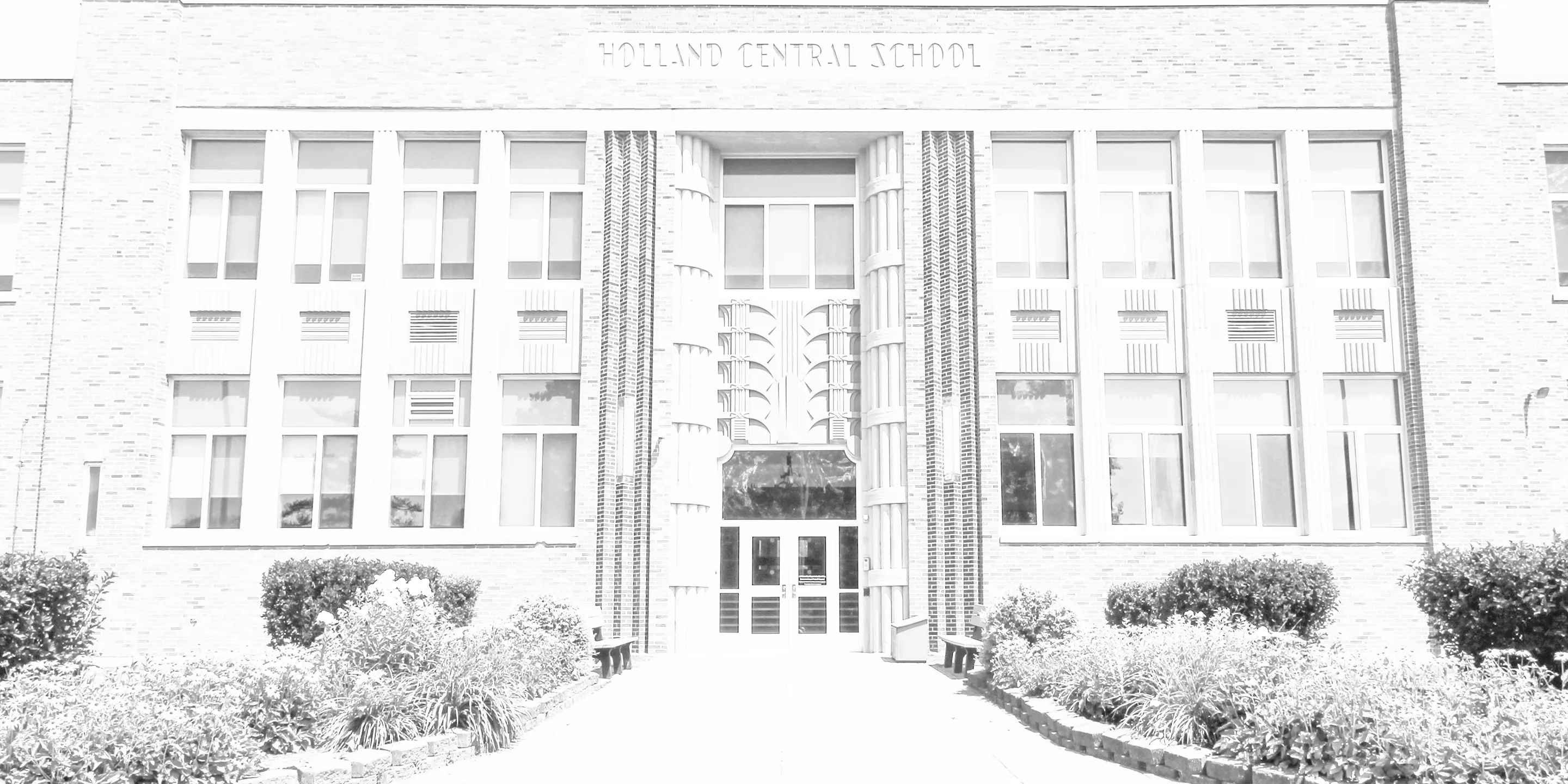 Front entrance of Holland Central School with large windows, decorative pillars, and landscaped bushes.