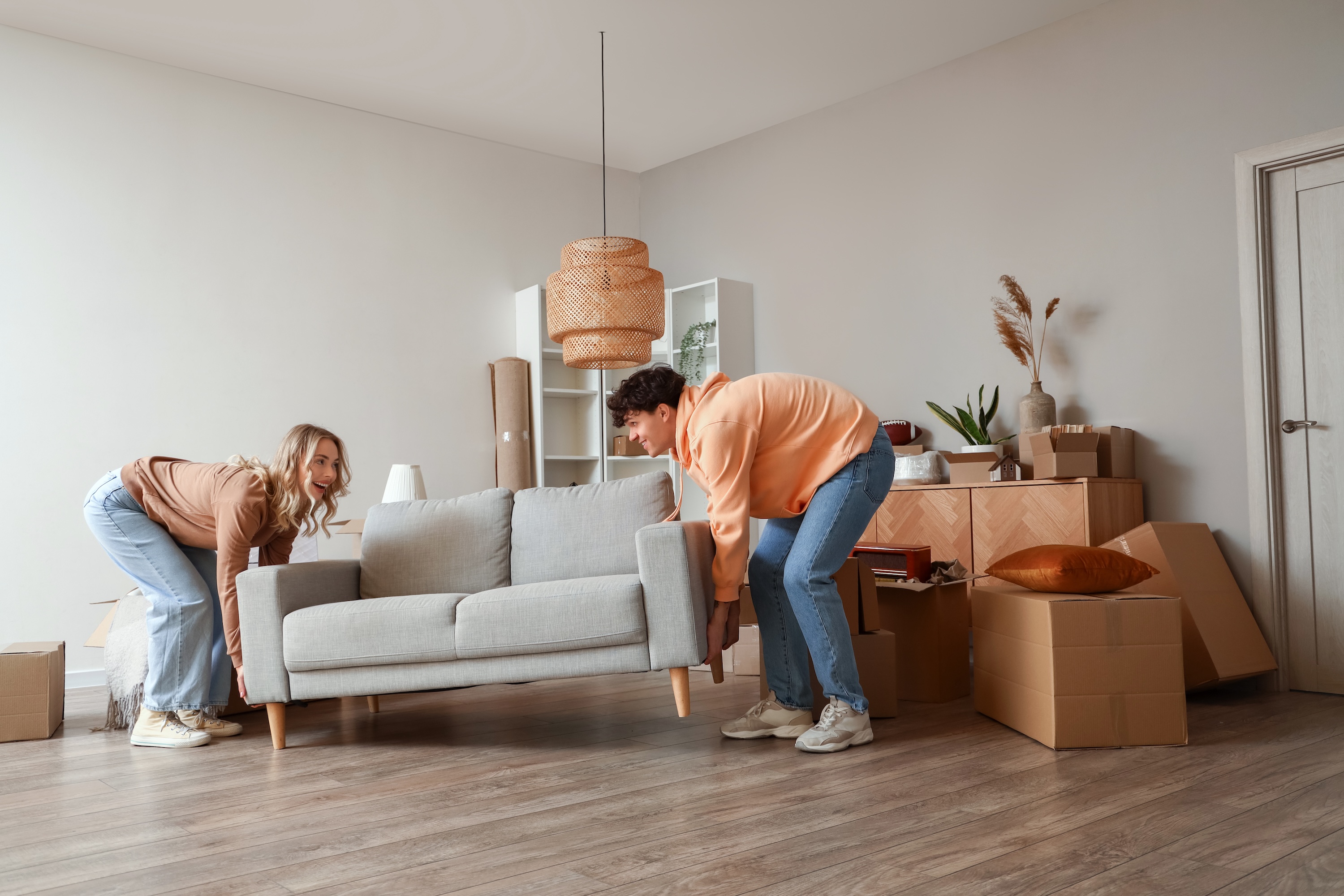 New residents moving furniture into a spacious living area at Adora at Rosehill in Tomball, showcasing the community's modern interiors and move-in ready apartments.