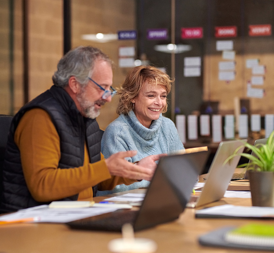 Two employees reviewing information on a laptop