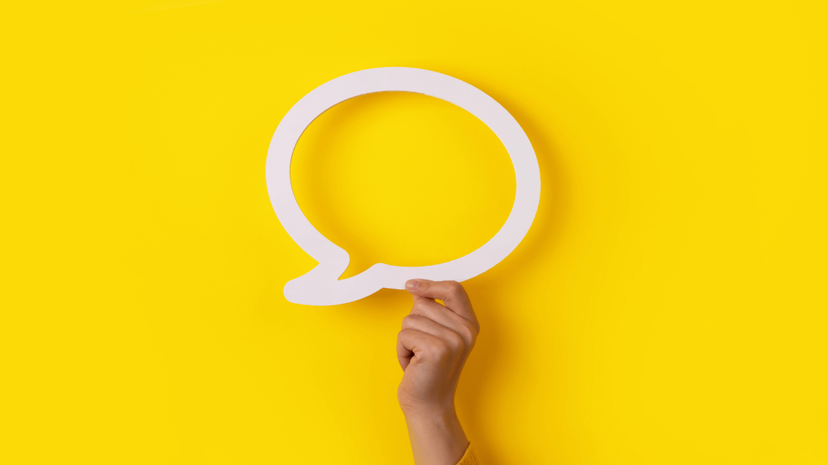 A person's hand holding a speech bubble icon