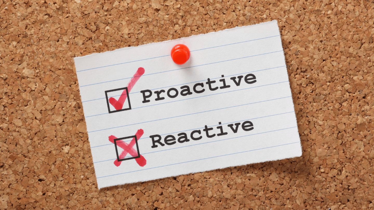 A small note pinned on a corkboard showing a checklist for Proactive and an x mark for Reactive