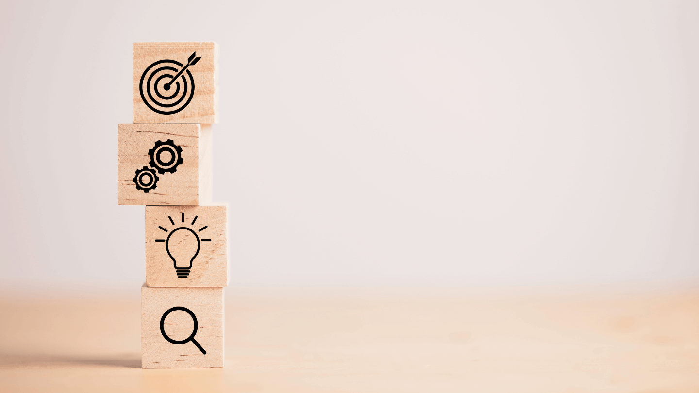 A wooden-cube with icons stacked into each other showing the process of reaching goals