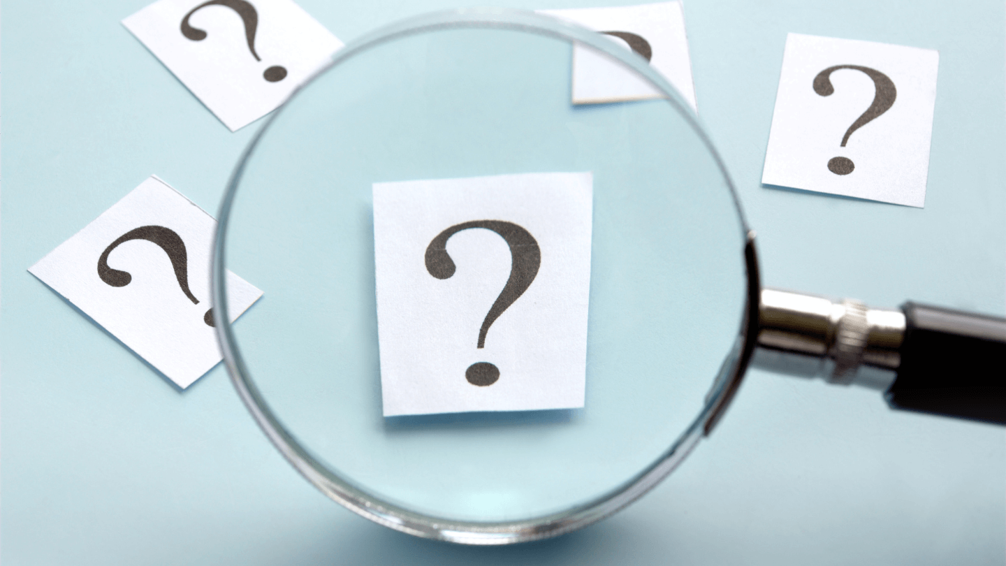 A magnifying glass looking through different question marks