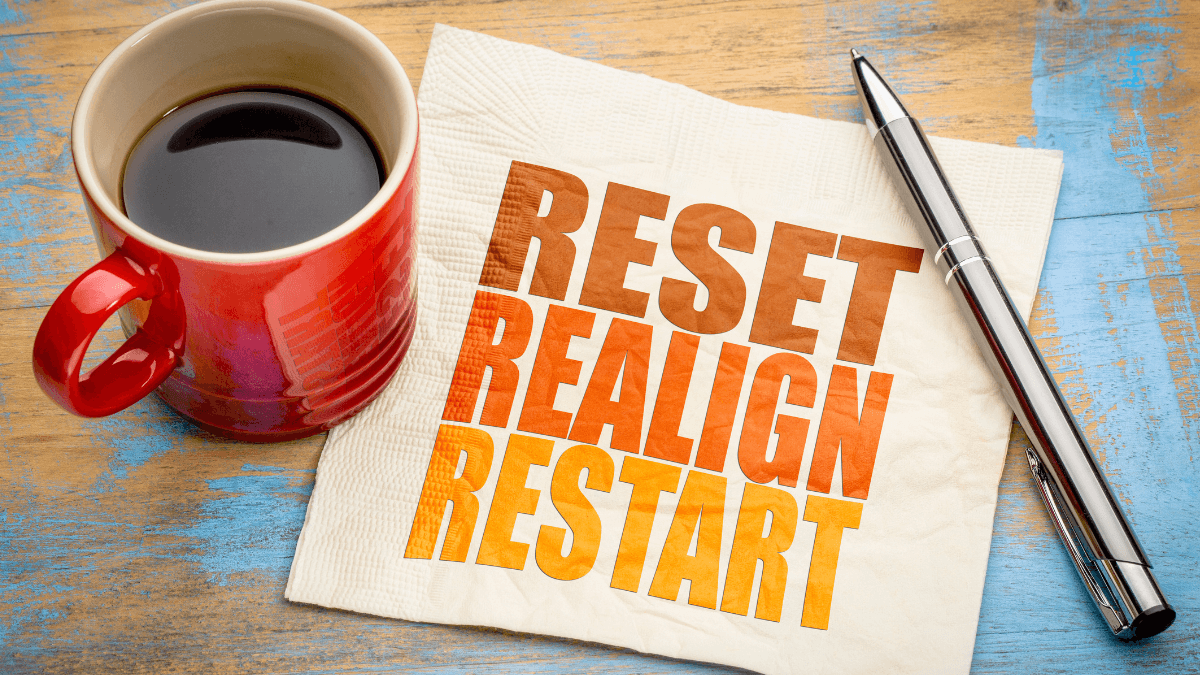 An image of a coffee, a tissue with text "Reset, Realign, Restart", and a pen on the table