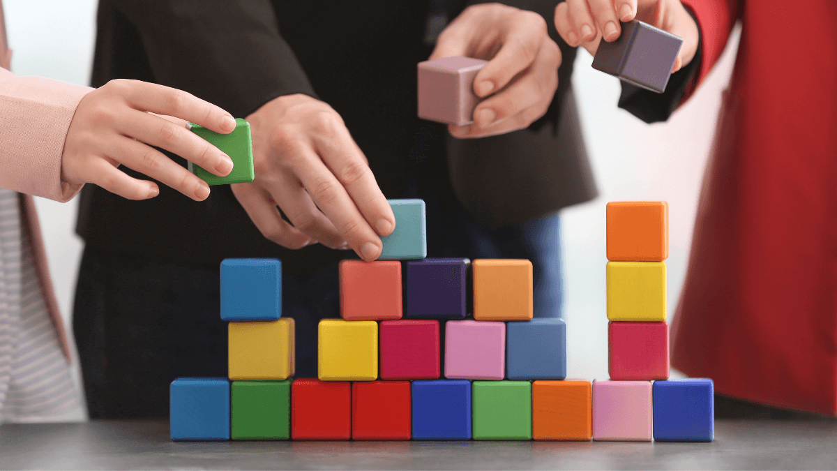 Three people stacking different colored blocks