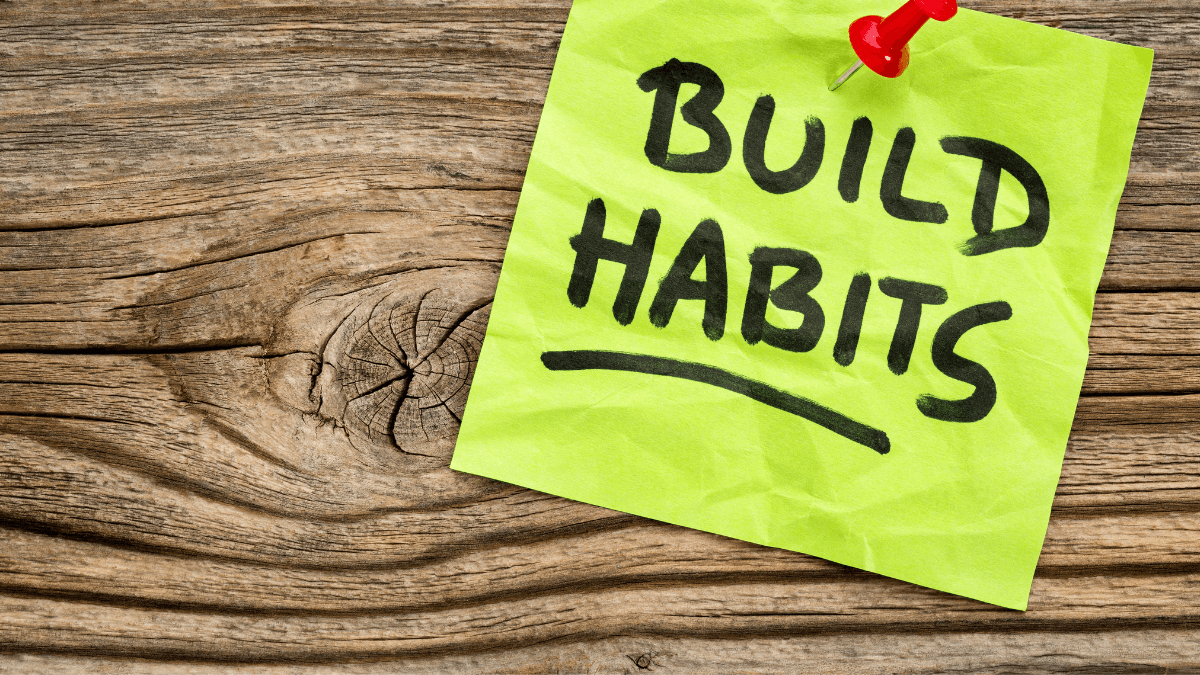 A notes saying, "Build habits" pinned on a wooden board