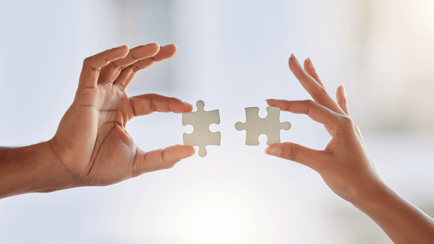 Two human hands fitting in two puzzle pieces together