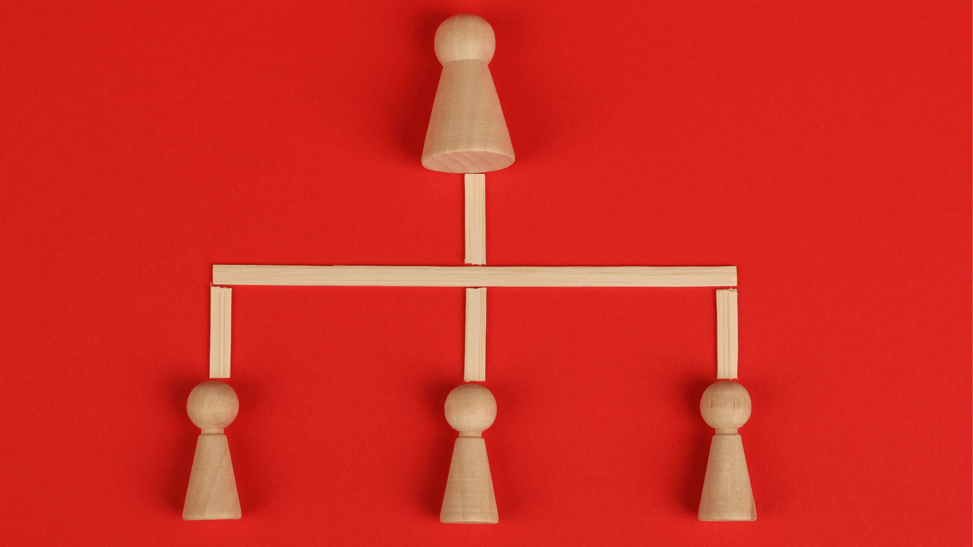 An image of wood figures illustrating a person on top with three subordinates