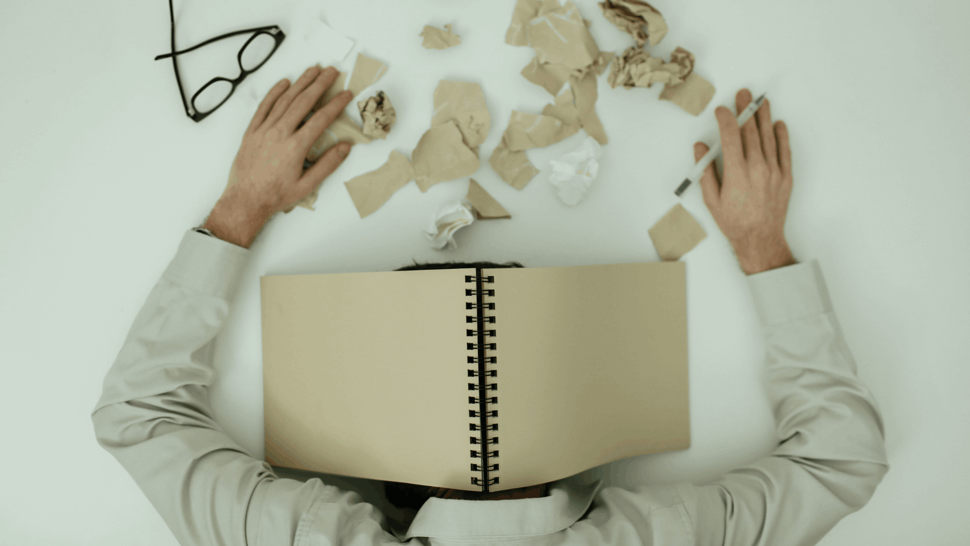A person that looks stressed with crumpled papers in front