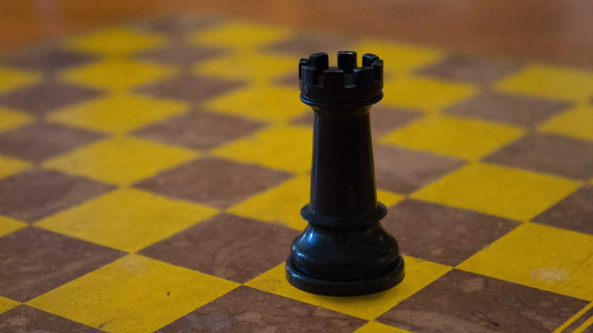A black chess piece on a wooden chessboard