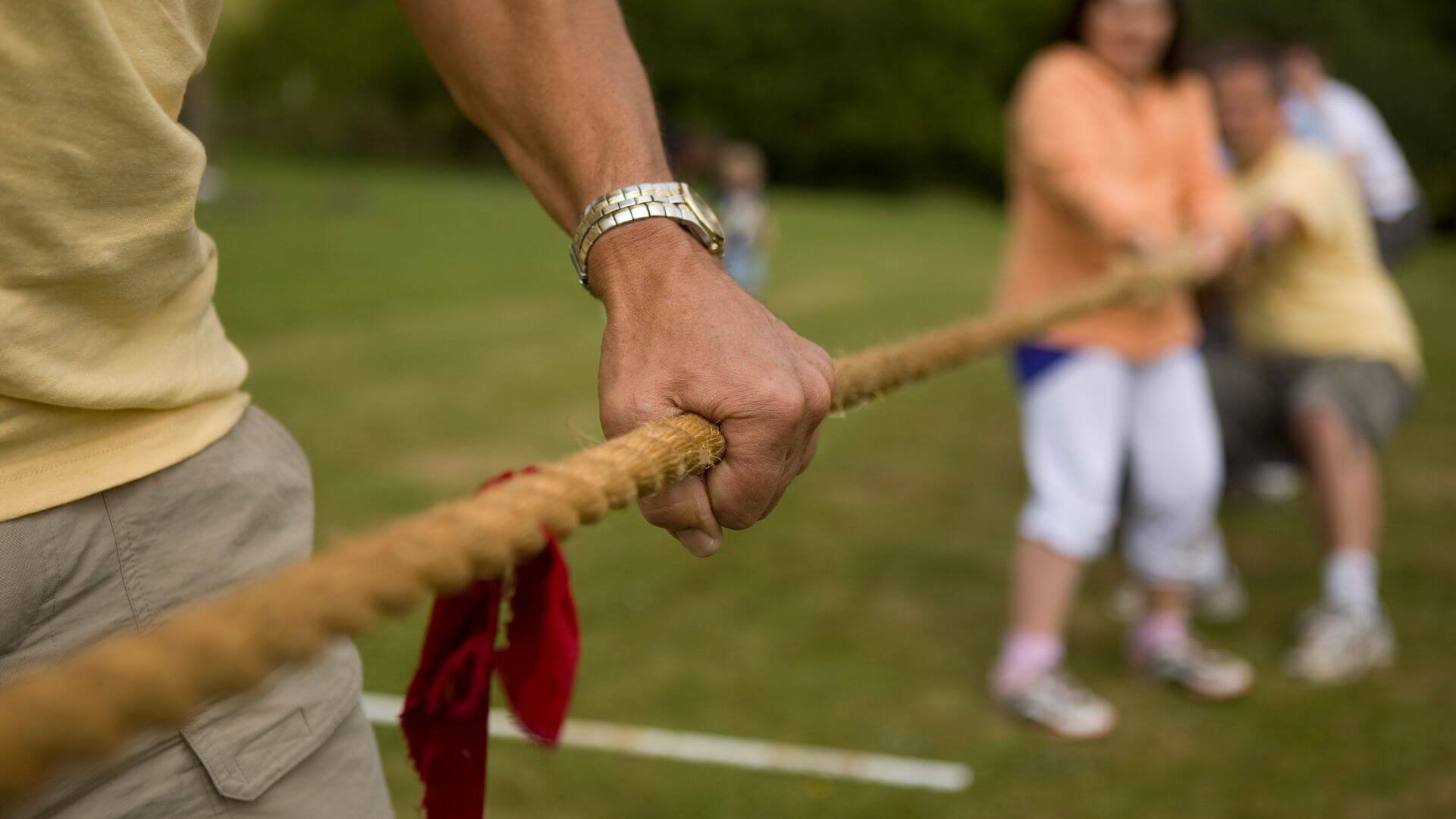 A person holding on the rope from the middle during a tug of war game