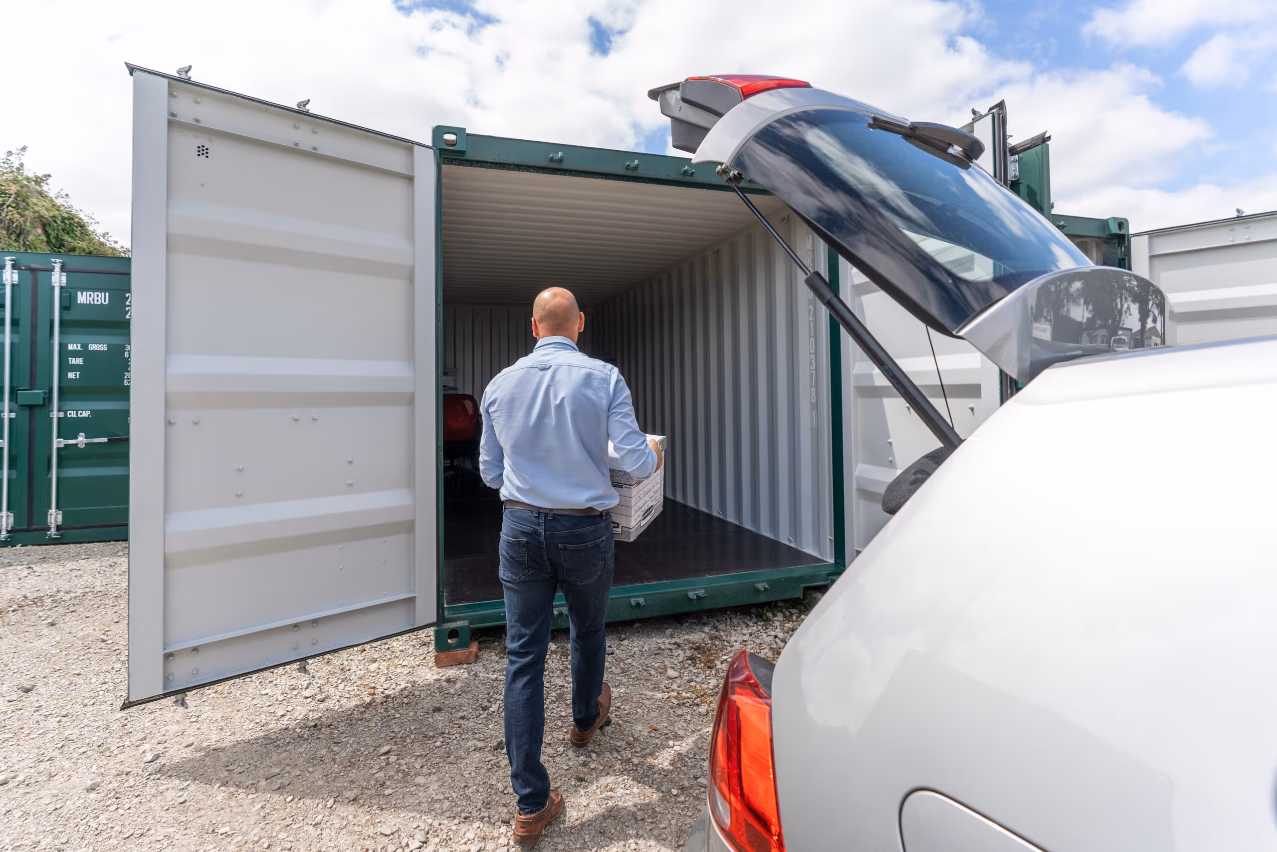 An image showing a man unloading boxes from his car and storing them in a Safe & Dry container