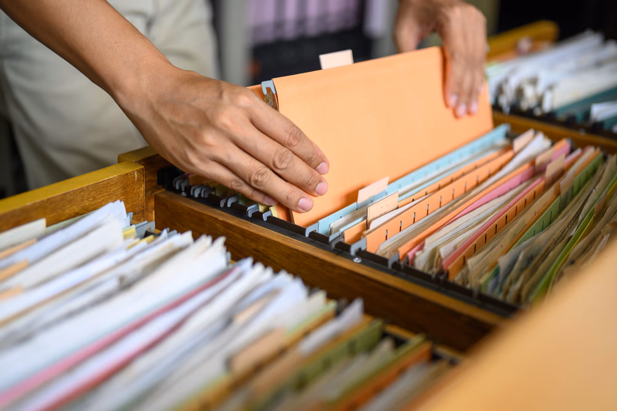 An image showing hands going through business documents in a filing unit