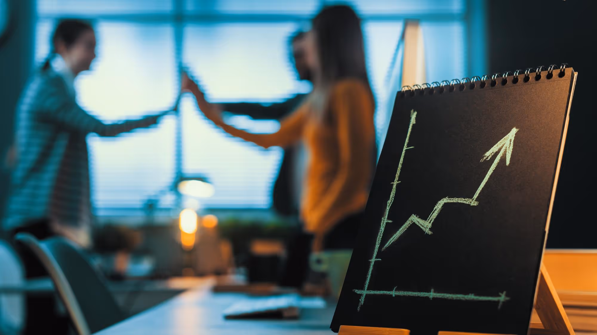 A generic image showing business people high-fiving in front of a growth trajectory graph