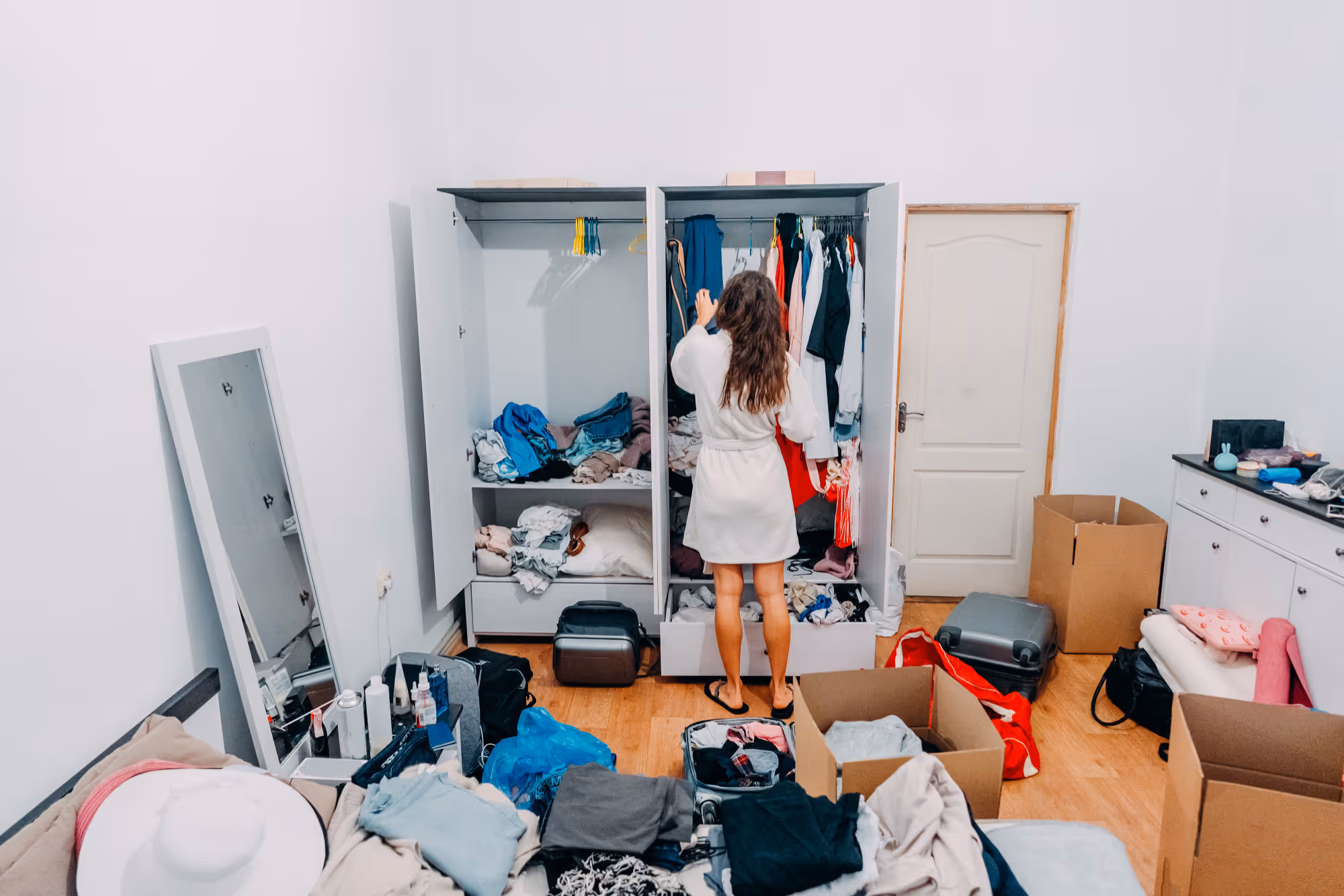 An image showing a woman going through her wardrobe as part of a decluttering process