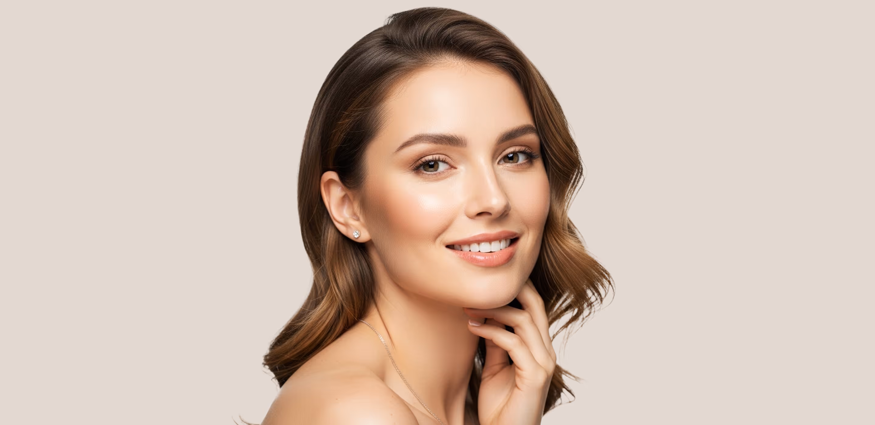 Smiling woman with clear skin touching her face gently on a gray background.
